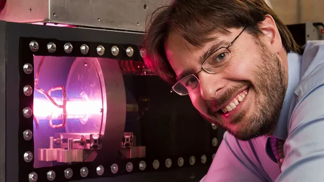 Greg Piefer of SHINE beside a glowing fusion device